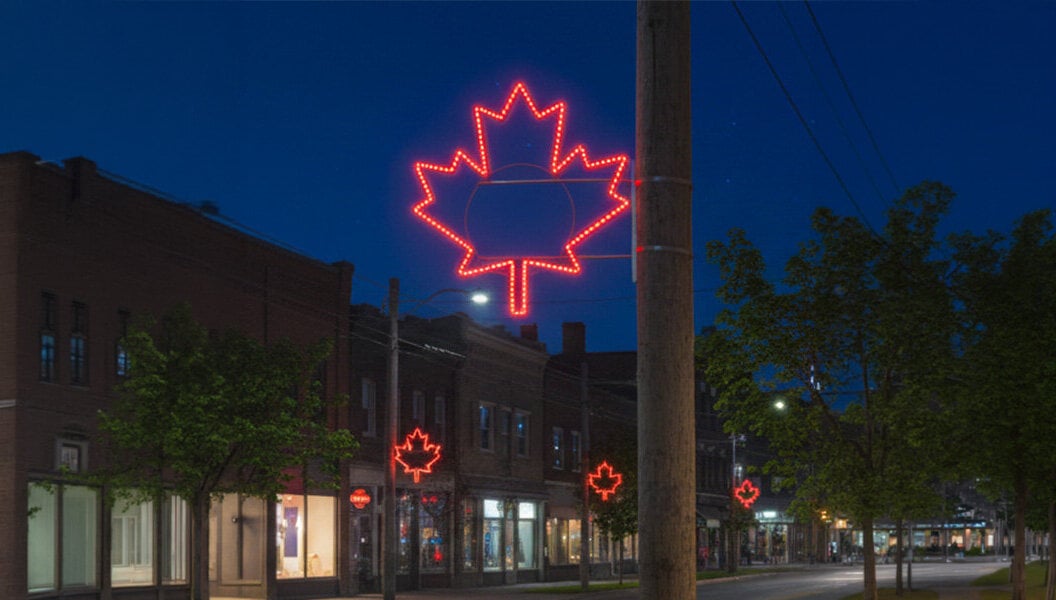 Illuminated maple leaf pole displays decorating a downtown street for Canada Day celebrations and municipal streetscape lighting.